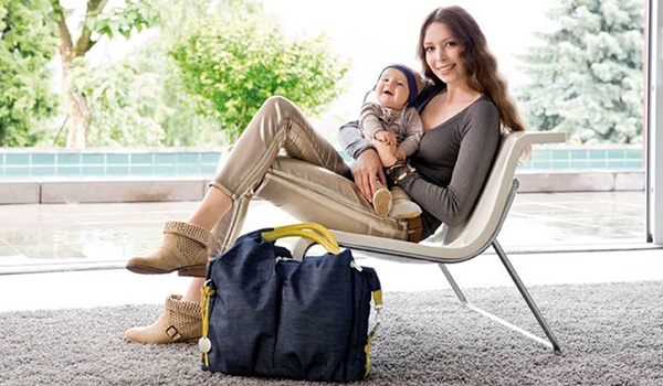 Sitzende Mama mit Baby und Wickeltasche