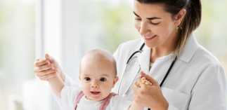 Ärztin hält Baby bei dem Armen, damit es steht